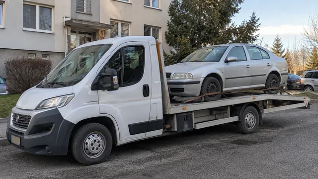 Bílý odtahový vůz s upevněným vozidlem Škoda na hliníkové plošině