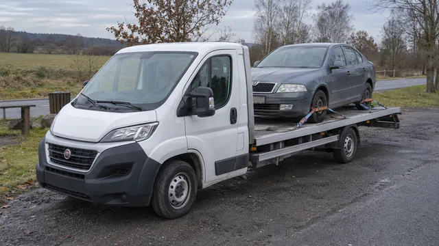 Bílý odtahový vůz s upevněným vozidlem Škoda na hliníkové plošině