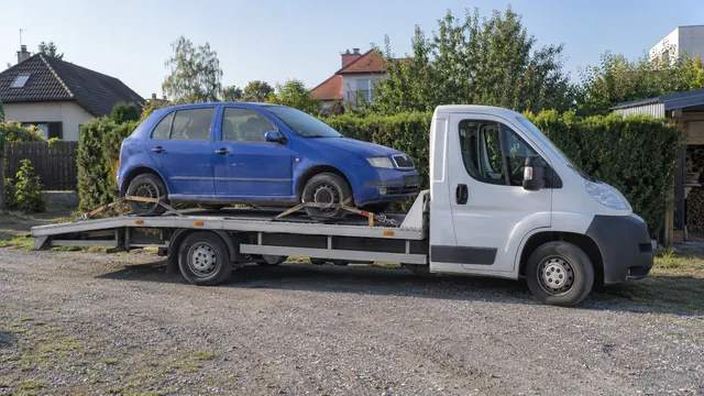 Bílý odtahový vůz s upevněným vozidlem Škoda na hliníkové plošině