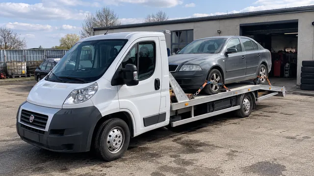 Bílý odtahový vůz s upevněným vozidlem Škoda na hliníkové plošině