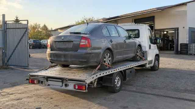 Bílý odtahový vůz s upevněným vozidlem Škoda na hliníkové plošině