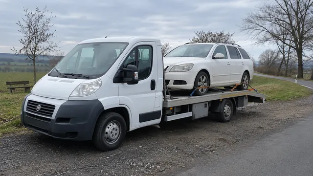 Bílý odtahový vůz s upevněným vozidlem Škoda na hliníkové plošině