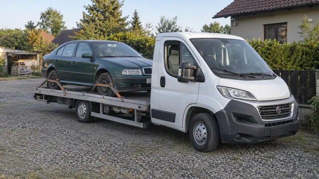 Bílý odtahový vůz s upevněným vozidlem Škoda na hliníkové plošině