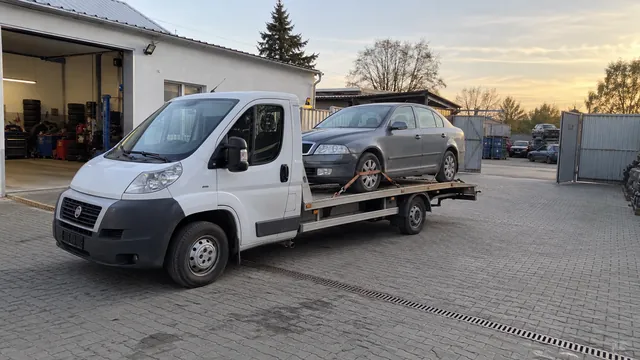 Bílý odtahový vůz s upevněným vozidlem Škoda na hliníkové plošině