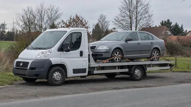 Bílý odtahový vůz s upevněným vozidlem Škoda na hliníkové plošině