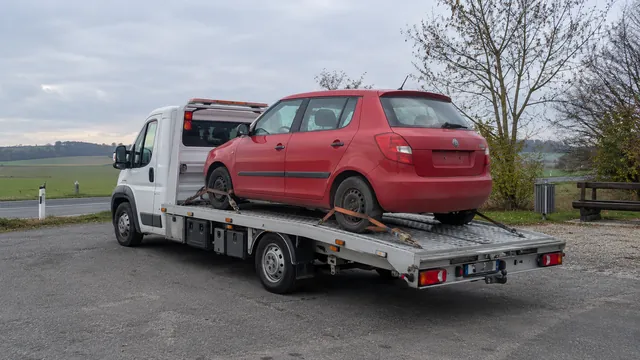 Bílý odtahový vůz s upevněným vozidlem Škoda na hliníkové plošině