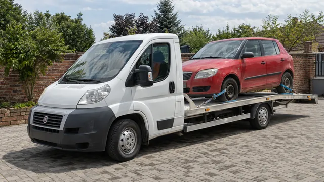 Bílý odtahový vůz s upevněným vozidlem Škoda na hliníkové plošině