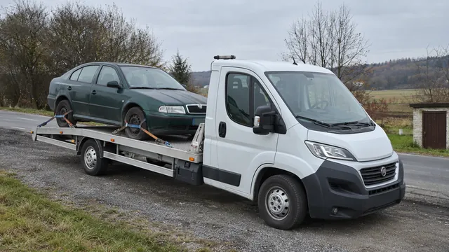 Bílý odtahový vůz s upevněným vozidlem Škoda na hliníkové plošině
