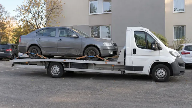 Bílý odtahový vůz s upevněným vozidlem Škoda na hliníkové plošině