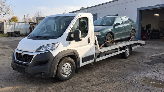 Bílý odtahový vůz s upevněným vozidlem Škoda na hliníkové plošině