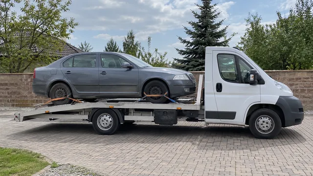 Bílý odtahový vůz s upevněným vozidlem Škoda na hliníkové plošině