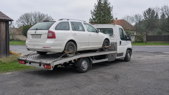 Bílý odtahový vůz s upevněným vozidlem Škoda na hliníkové plošině