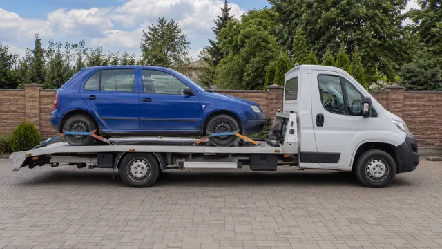 Bílý odtahový vůz s upevněným vozidlem Škoda na hliníkové plošině