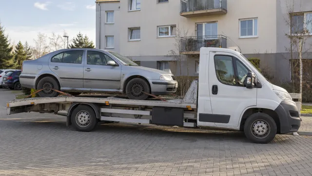 Bílý odtahový vůz s upevněným vozidlem Škoda na hliníkové plošině