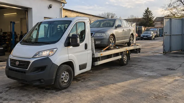 Bílý odtahový vůz s upevněným vozidlem Škoda na hliníkové plošině