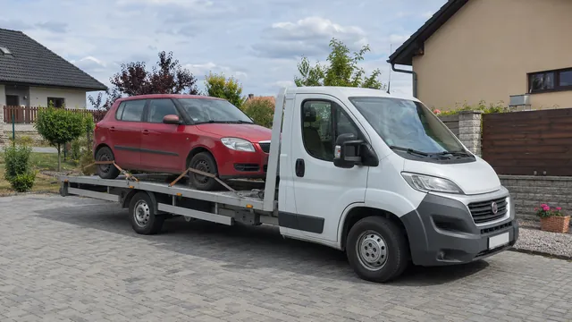 Bílý odtahový vůz s upevněným vozidlem Škoda na hliníkové plošině