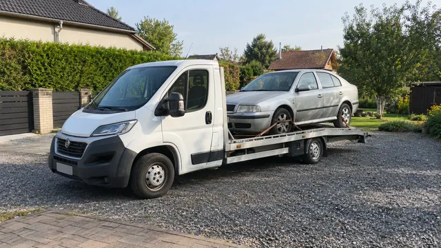 Bílý odtahový vůz s upevněným vozidlem Škoda na hliníkové plošině