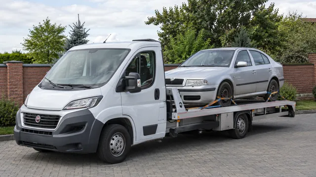 Bílý odtahový vůz s upevněným vozidlem Škoda na hliníkové plošině