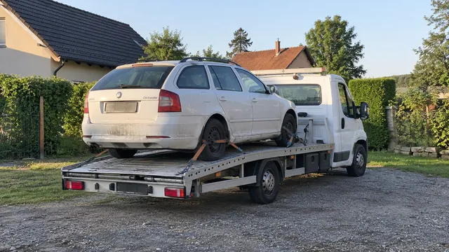 Bílý odtahový vůz s upevněným vozidlem Škoda na hliníkové plošině