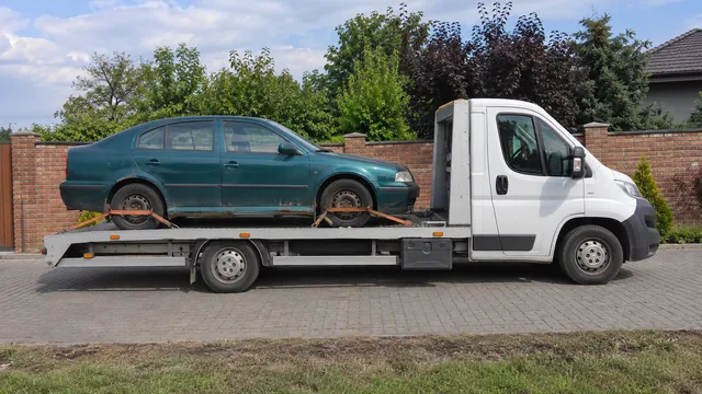 Bílý odtahový vůz s upevněným vozidlem Škoda na hliníkové plošině
