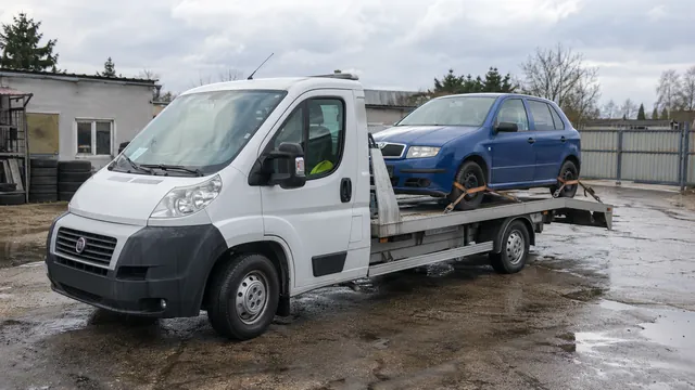 Bílý odtahový vůz s upevněným vozidlem Škoda na hliníkové plošině