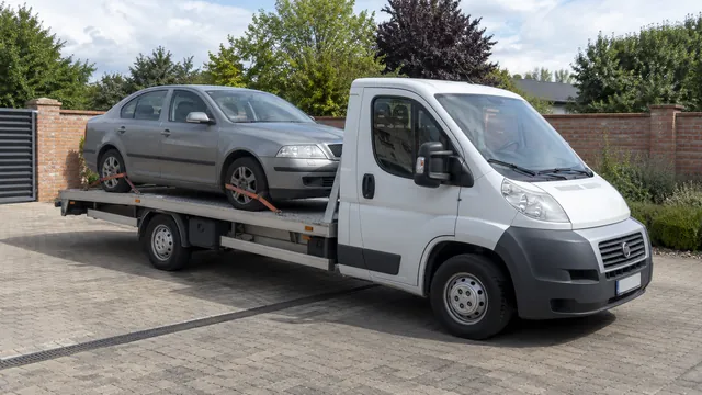 Bílý odtahový vůz s upevněným vozidlem Škoda na hliníkové plošině