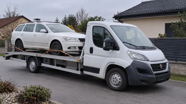 Bílý odtahový vůz s upevněným vozidlem Škoda na hliníkové plošině