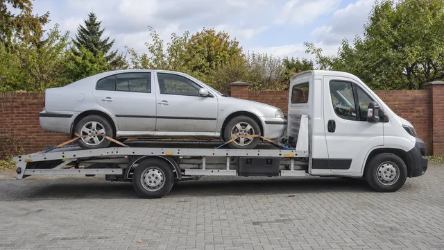Bílý odtahový vůz s upevněným vozidlem Škoda na hliníkové plošině