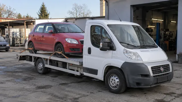 Bílý odtahový vůz s upevněným vozidlem Škoda na hliníkové plošině