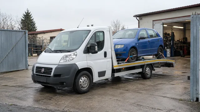 Bílý odtahový vůz s upevněným vozidlem Škoda na hliníkové plošině