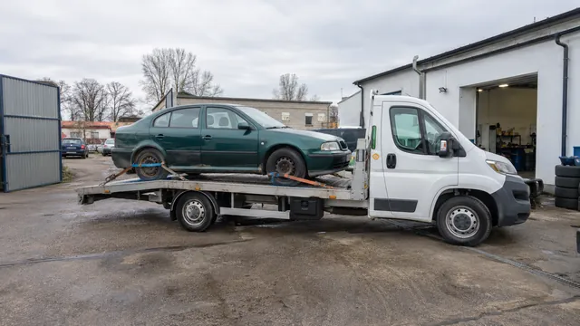Bílý odtahový vůz s upevněným vozidlem Škoda na hliníkové plošině