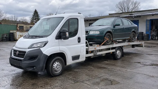 Bílý odtahový vůz s upevněným vozidlem Škoda na hliníkové plošině