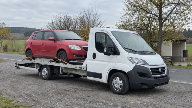 Bílý odtahový vůz s upevněným vozidlem Škoda na hliníkové plošině