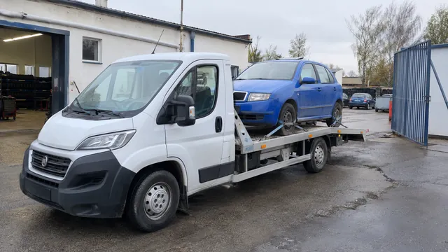 Bílý odtahový vůz s upevněným vozidlem Škoda na hliníkové plošině