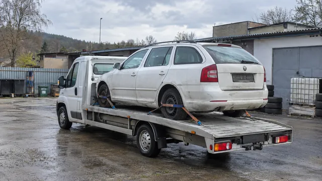Bílý odtahový vůz s upevněným vozidlem Škoda na hliníkové plošině