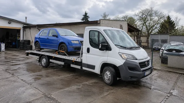 Bílý odtahový vůz s upevněným vozidlem Škoda na hliníkové plošině