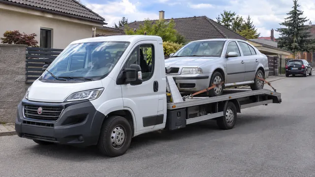 Bílý odtahový vůz s upevněným vozidlem Škoda na hliníkové plošině