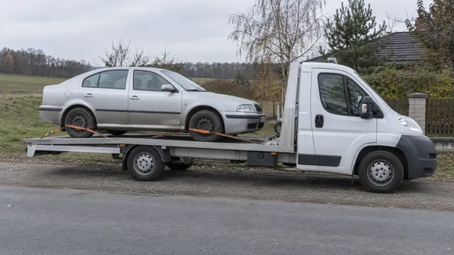 Bílý odtahový vůz s upevněným vozidlem Škoda na hliníkové plošině