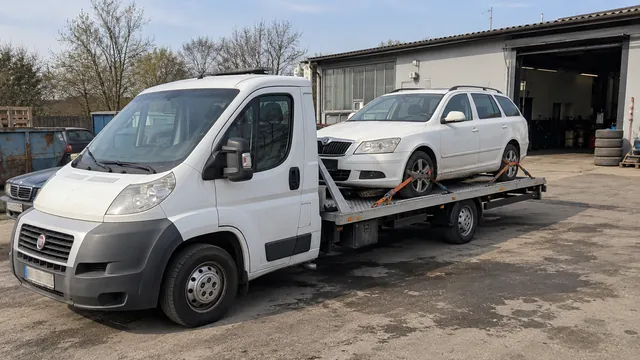 Bílý odtahový vůz s upevněným vozidlem Škoda na hliníkové plošině