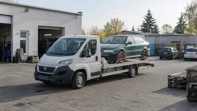 Bílý odtahový vůz s upevněným vozidlem Škoda na hliníkové plošině