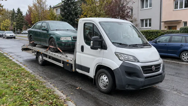 Bílý odtahový vůz s upevněným vozidlem Škoda na hliníkové plošině