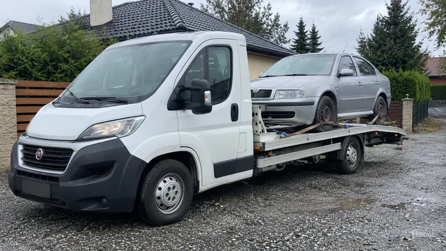 Bílý odtahový vůz s upevněným vozidlem Škoda na hliníkové plošině