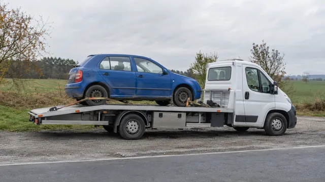 Bílý odtahový vůz s upevněným vozidlem Škoda na hliníkové plošině