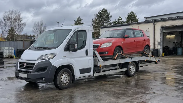 Bílý odtahový vůz s upevněným vozidlem Škoda na hliníkové plošině