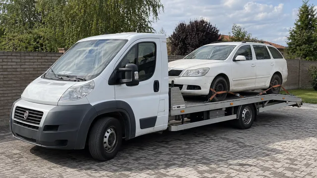 Bílý odtahový vůz s upevněným vozidlem Škoda na hliníkové plošině