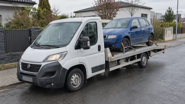 Bílý odtahový vůz s upevněným vozidlem Škoda na hliníkové plošině