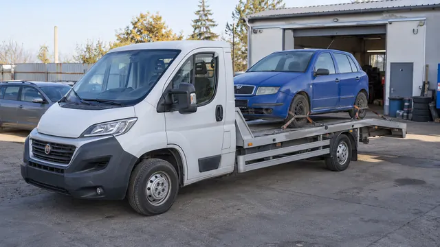 Bílý odtahový vůz s upevněným vozidlem Škoda na hliníkové plošině