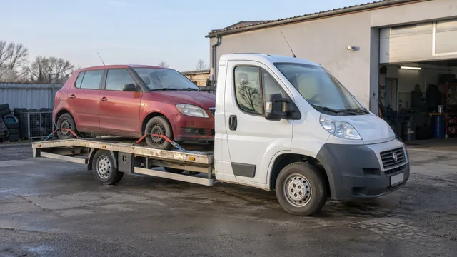 Bílý odtahový vůz s upevněným vozidlem Škoda na hliníkové plošině