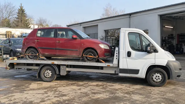 Bílý odtahový vůz s upevněným vozidlem Škoda na hliníkové plošině