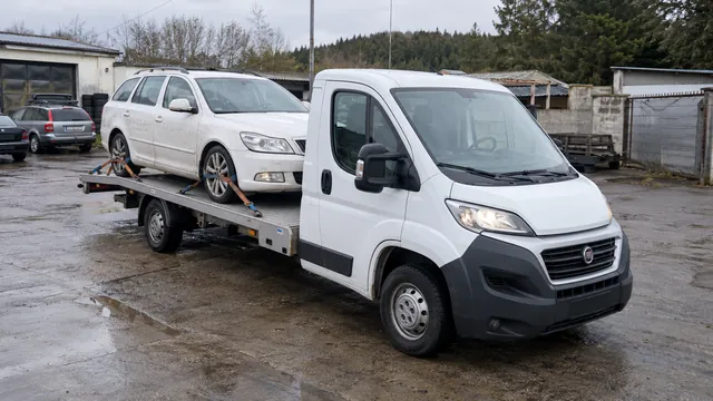 Bílý odtahový vůz s upevněným vozidlem Škoda na hliníkové plošině